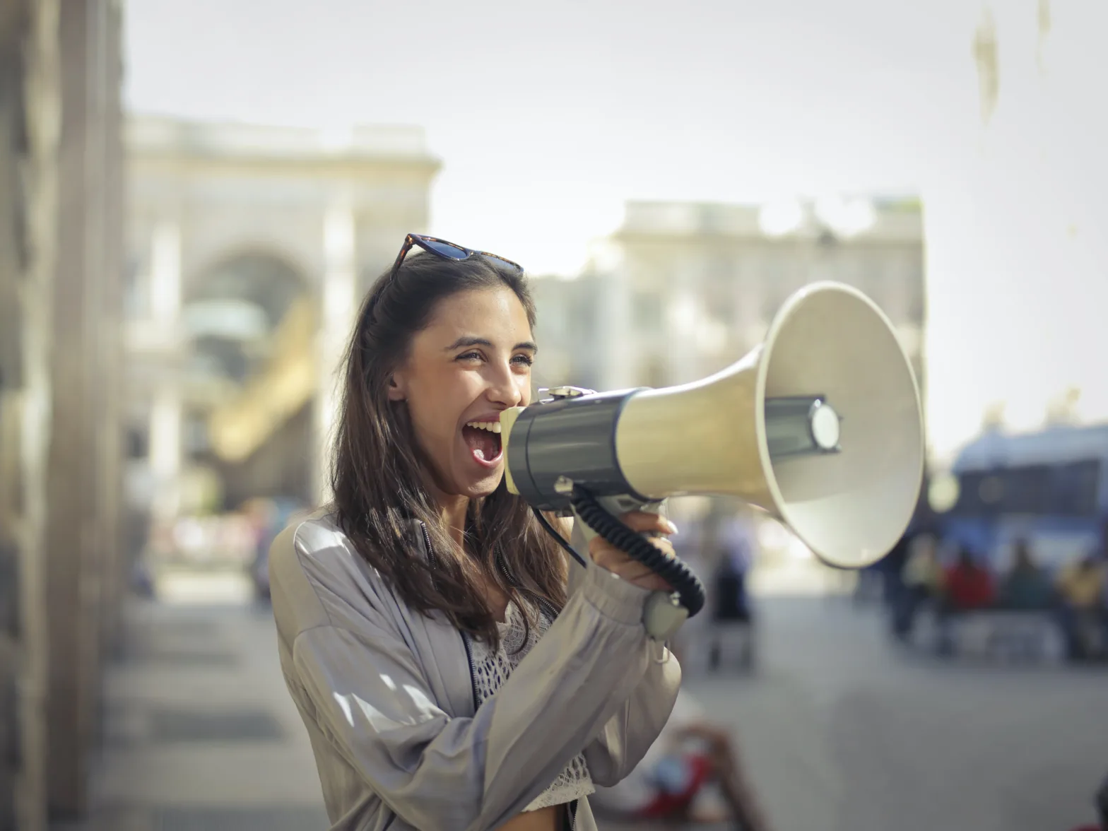 Cheerful young woman yelling into megaphone.