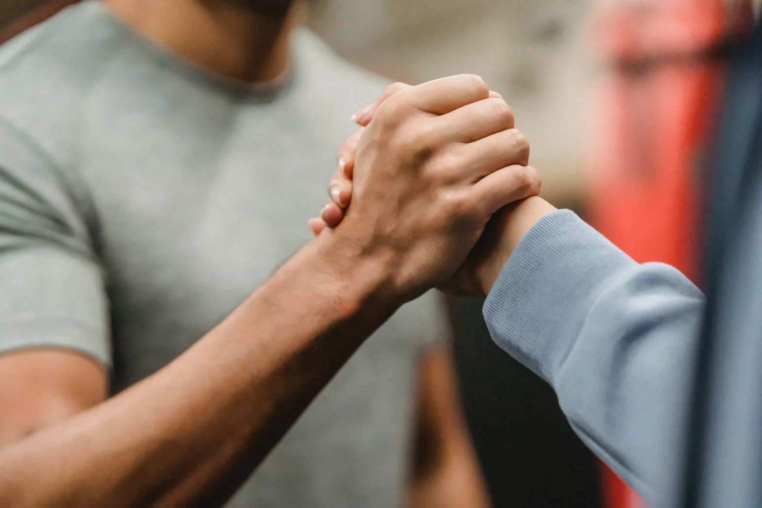 Two people clasping hands in a gym.